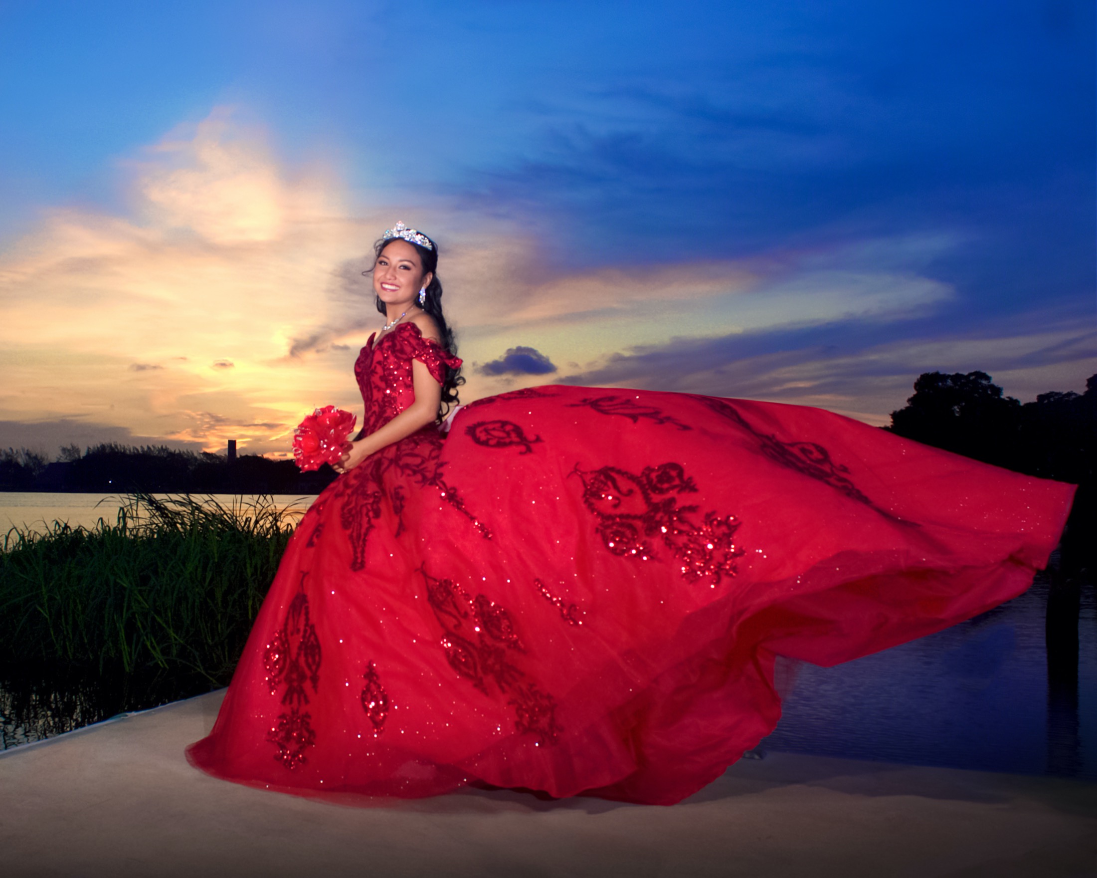 Quinceañera con vestido rojo fotografiada al atardecer