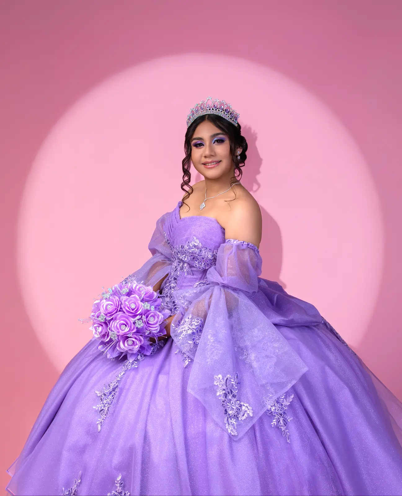 Quinceañera con vestido lila sobre fondo rosa